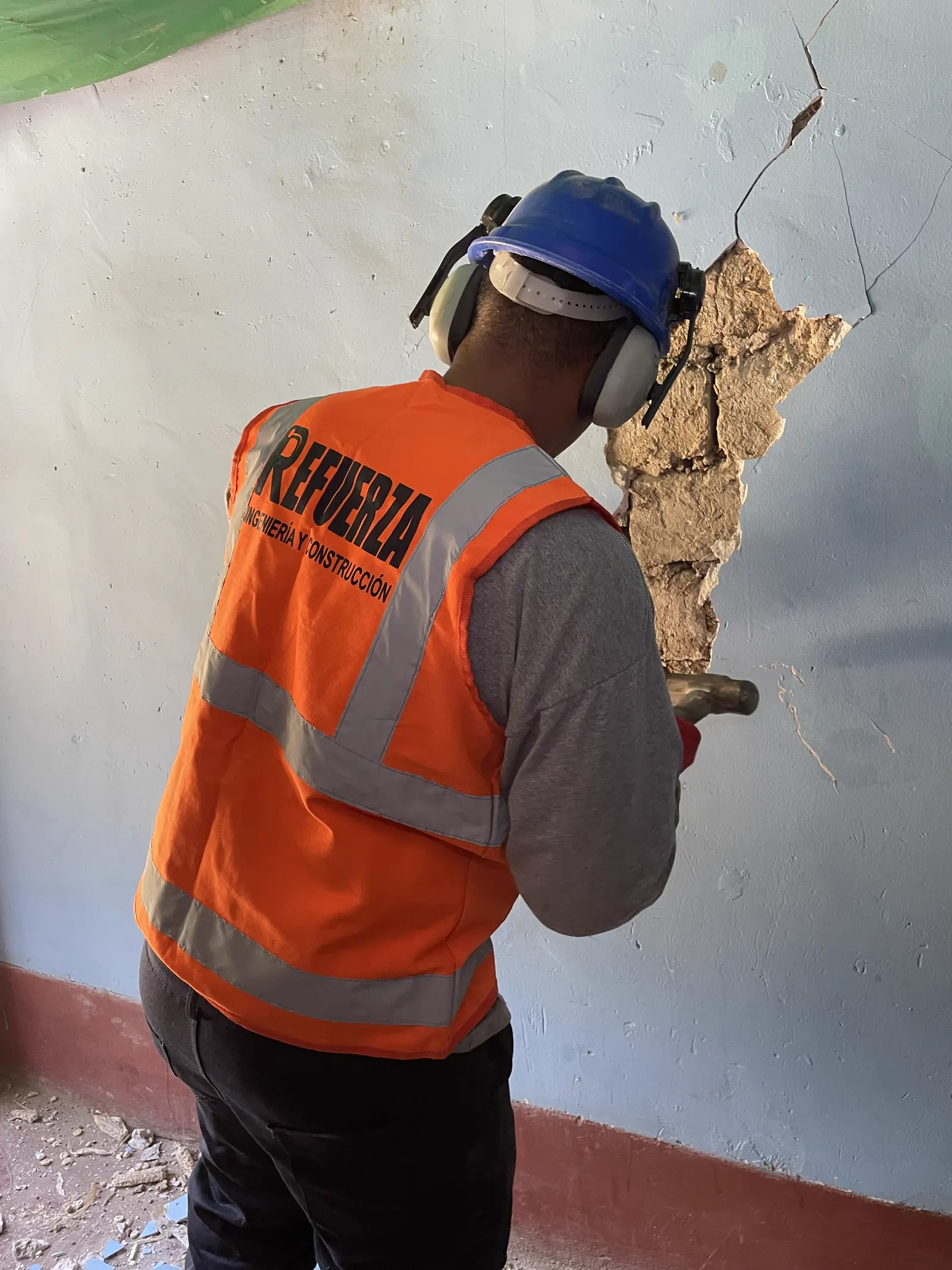 Trabajador retirando tarrajeo suelto en un muro interior